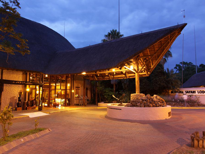 Sweeping thatched entrance canopy of Cresta Mowana Safari Lodge lit at dusk, Chobe area, Botswana